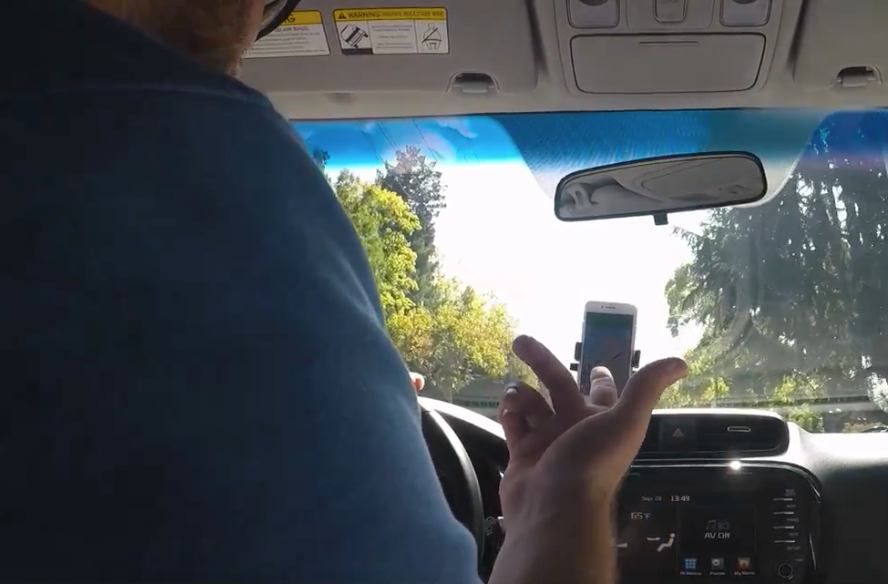 View from the passenger seat during a ride-along study — a driver interacts with a phone mounted in a testing vehicle on public roads.