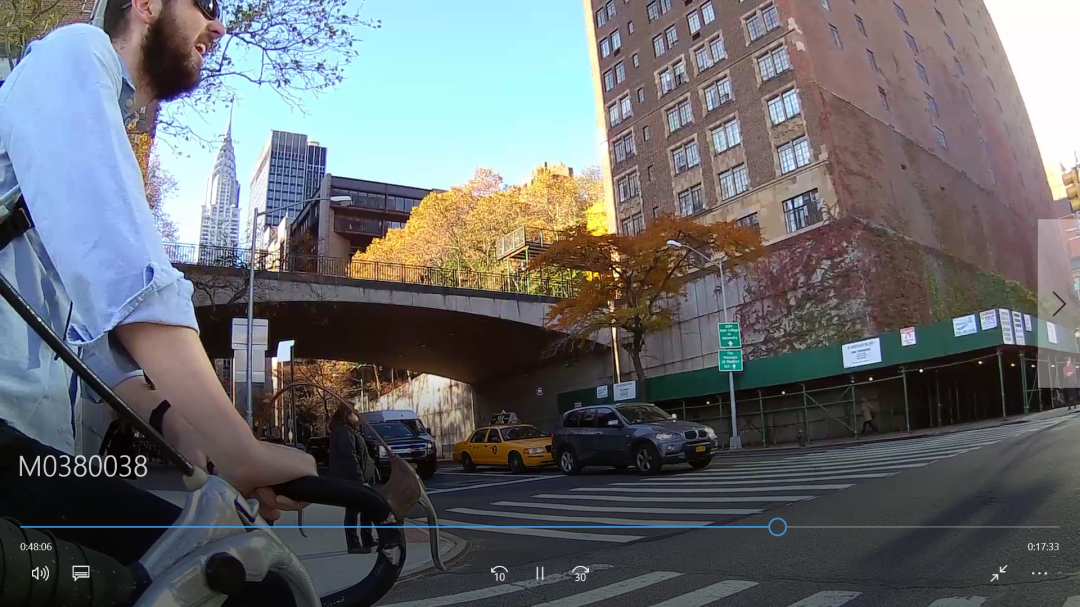 A small action camera mounted to the handlebars of a road bike with tangled earbuds beside it — the chase bike's recording rig.